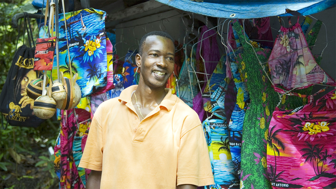 Young Jamaican man showing souvenirs to tourists