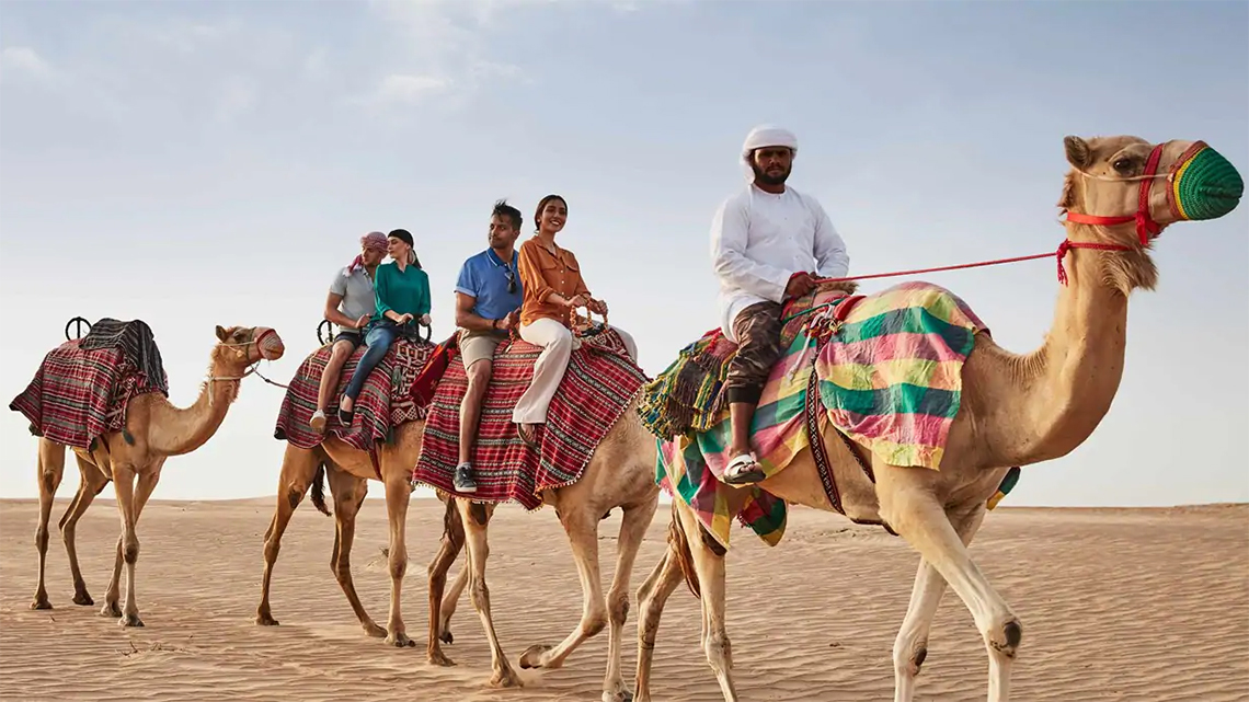 Tourists riding camels on a desert safari in Dubai